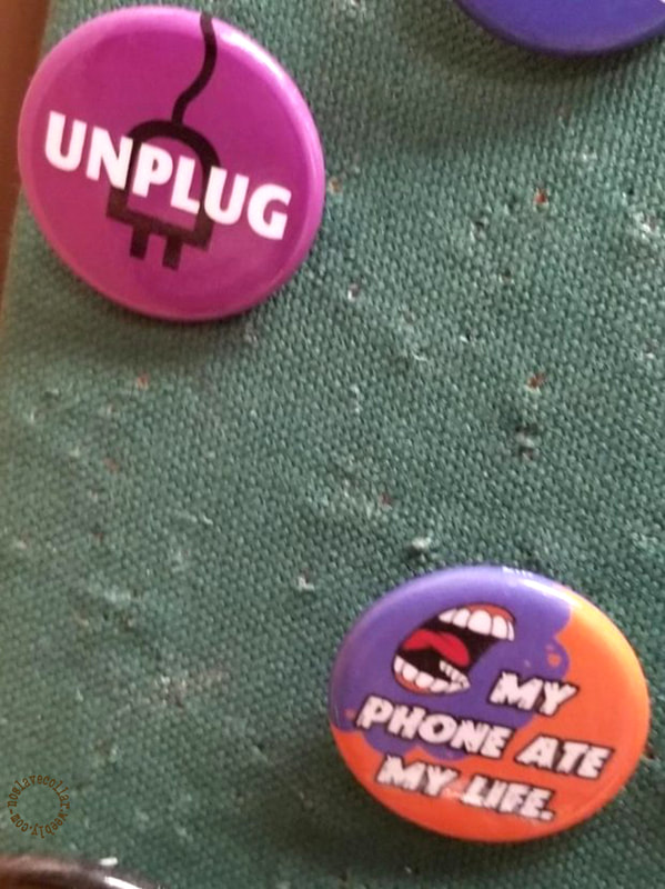 Pins vus dans un magasin de jeux de société: "Débranchez" et "Mon téléphone a dévoré ma vie."